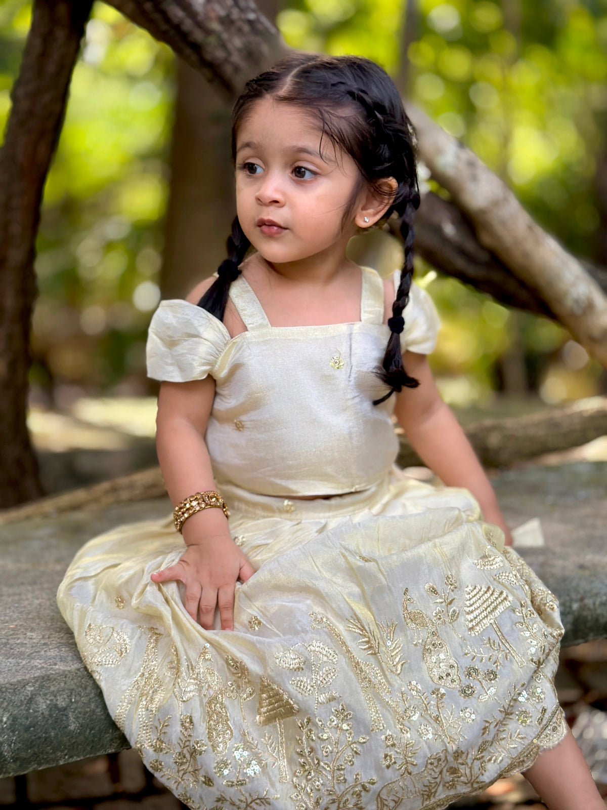 A young girl in an ivory Nuts skirt and top set, seated outdoors